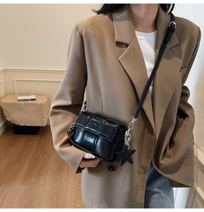 Détail du sac carré tressé noir avec chaîne argentée et accessoire pendentif étoile