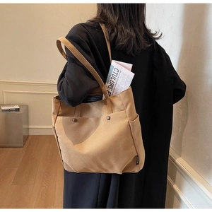 Detail of khaki canvas tote bag with vintage front pockets and soft shoulder strap design