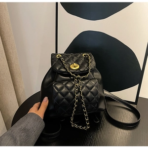Gros plan sur la texture en cuir matelassé noir et le fermoir doré de ce sac à dos