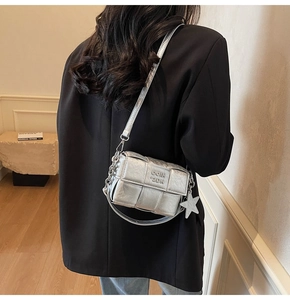 Détail du sac bandoulière tressé argenté avec chaîne et pendentif étoile sur blazer