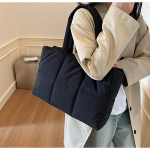 Detailed view of black quilted puffer tote bag worn crossbody for winter style