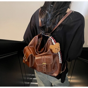 Detailed view of the vintage brown faux leather backpack with plush bear and metal buckles