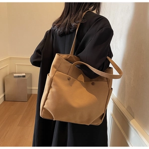 Detailed view of camel canvas tote bag with dual handles and side pocket on model