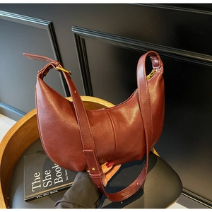 Detail of burgundy hobo bag in synthetic leather with adjustable strap on a chair