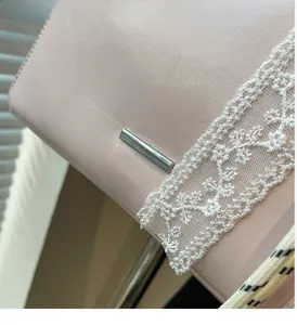 Close-up of pink leather bucket bag featuring silver hardware and white lace detail