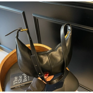 Detail of black crescent hobo bag featuring smooth leather and gold metal buckle accents
