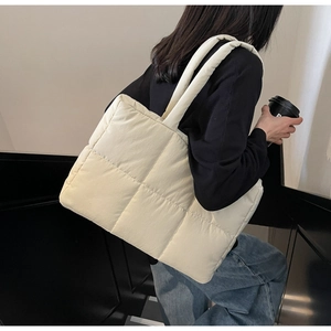 Close-up of quilted cream tote bag showing soft padded texture and large capacity