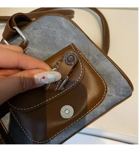 Detail of retro contrast shoulder bag featuring leather, denim stitch, and silver buckle