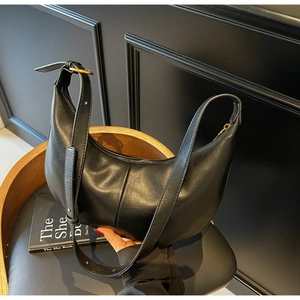 Detail of black crescent hobo bag featuring pebbled leather and gold metal buckle strap