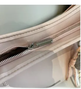 Detail of a pink leather bucket bag showing silver metal zipper and woven pendant charm