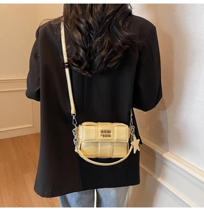 Détail du sac carré tressé beige avec logo en métal doré et accessoire pendentif étoile