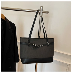 Detail der grauen Twill- und schwarzen Ledertasche mit Metallschnalle am Kleiderbügel
