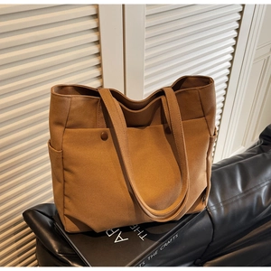 Detail of caramel canvas tote bag showing front pockets with antique copper snaps and textures