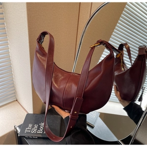 Detail of burgundy crescent shoulder bag with polished leather and adjustable strap