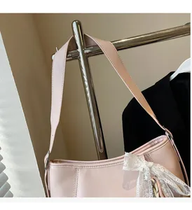 Detail of pink PU leather bag featuring elegant white lace bow and durable wide strap