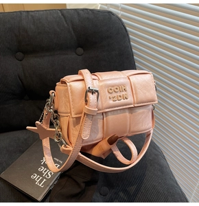 Détail du sac bandoulière tissé rose avec logo métallique et pendentif étoile au bras