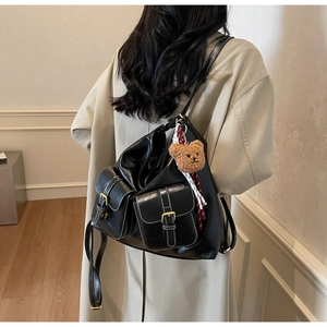 Detail of black PU leather backpack with two front pockets and a brown bear pendant