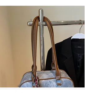 Detail of retro denim Boston bag featuring brown leather handles and sturdy silver hardware