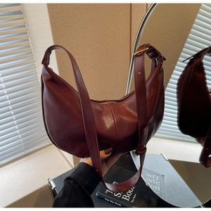 Close-up of wine red crescent bag with adjustable strap and premium leather texture