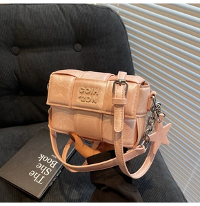 Détail du sac bandoulière rose tressé avec pendentif étoile sur velours noir