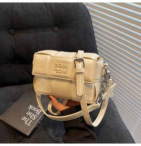Détail d'un sac bandoulière tressé crème avec pendentif étoile et chaîne argentée