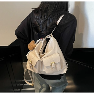 Beige oversized tote bag with dual front flap pockets shown on a model on stairs