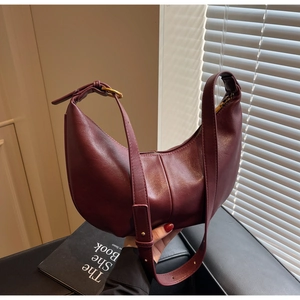 Close-up of burgundy leather hobo bag featuring gold ring hardware and wide shoulder strap