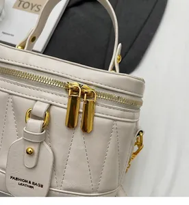 Detail der cremefarbenen gesteppten Leder-Beuteltasche mit goldenen Reißverschlüssen