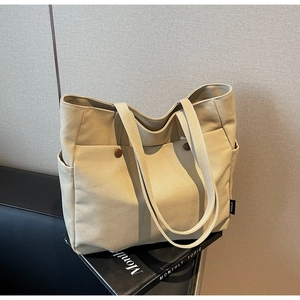 Detailed view of canvas tote bag with multi-pocket design and brown decorative buckles