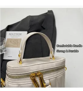 Detail der cremefarbenen Stepptasche mit goldenen Doppel-Reißverschlüssen und Metallgriffen