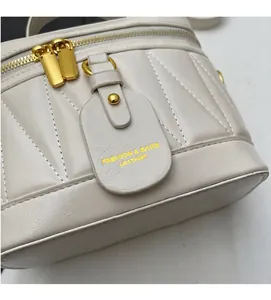 Nahaufnahme der cremefarbenen Beuteltasche mit Steppmuster und goldenem Reißverschluss