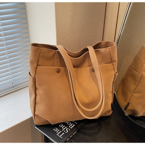 Detailed view of brown canvas tote bag with functional front pockets and dual straps