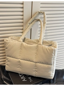 Chic beige quilted puffer tote bag with comfortable handles in a modern minimalist setting