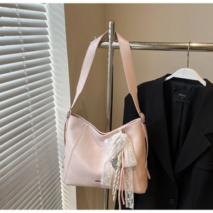 Pink crescent shoulder bag featuring a white lace bow and colorful tassel detail