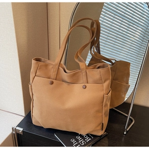 Detail view of caramel canvas tote bag with side pockets and stylish round buttons