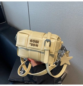 Détails d'un sac à bandoulière tressé jaune crème avec une breloque étoile métallique