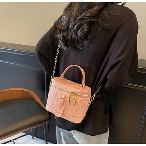 Rosafarbene Stepptasche aus Leder mit Goldkette zum schwarzen Outfit kombiniert