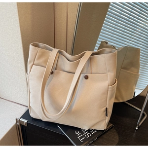 Detail view of beige canvas tote bag with multi-pocket design and long shoulder straps