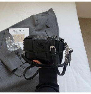 Détail du petit sac tissé noir avec chaîne argentée et bandoulière en cuir