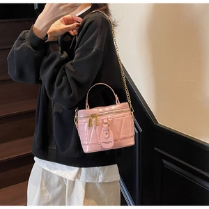 Rosafarbene gesteppte Vanity Bag mit Goldkette und Griff an der Schulter des Models