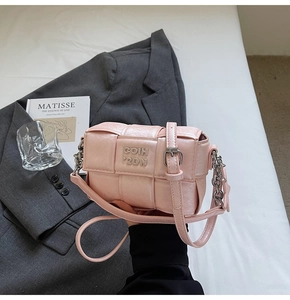 Vue détaillée du sac bandoulière rose tressé avec logo en métal et chaîne argentée