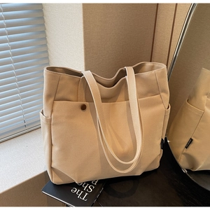 Detail of canvas tote bag with front button pocket and side compartments in beige