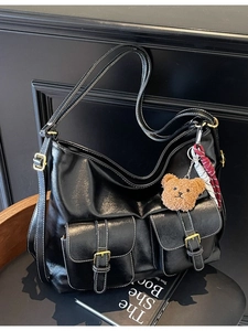 Vintage black faux leather hobo tote bag with bear charm and decorative scarf on books