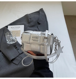 Détail d'un petit sac tissé argenté avec pendentif étoile et logo en relief