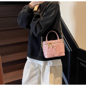 Detail der rosa glänzenden gesteppten Mini-Tasche mit Goldkette am Modell