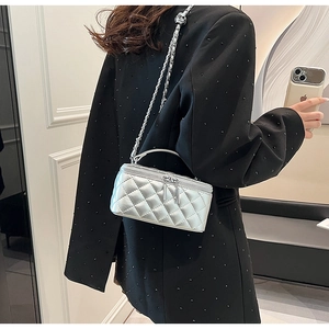 Close-up of silver quilted chain bag worn by model showing mini box style and metallic finish