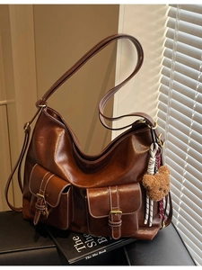 Vintage brown tote bag with contrast stitching and bear charm in a lifestyle setting