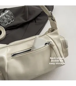 Detail einer beigen PU-Handtasche mit einer funktionellen Reißverschlusstasche auf der Rückseite