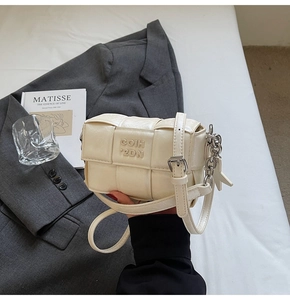 Vue détaillée du cuir tressé du sac carré crème avec chaîne étoilée argentée et logo