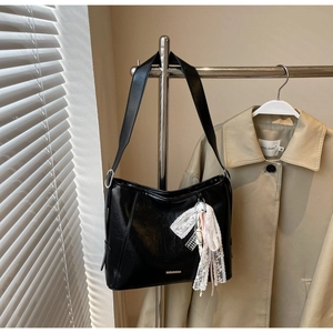 Detail of black large capacity shoulder bag with silver buckle and white lace ribbon